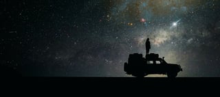 Silhouette on car against night sky hero crop