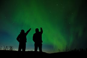 People pointing up at aurora