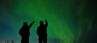 People pointing up at aurora